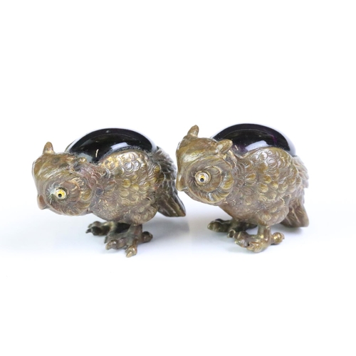 261 - A set of four bronze owl figures set with coloured glass backs.