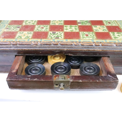 284 - An antique glassed topped chequers board complete with boxwood chequers within drawer.