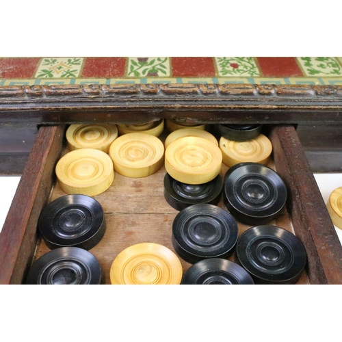 284 - An antique glassed topped chequers board complete with boxwood chequers within drawer.