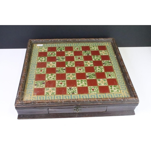 284 - An antique glassed topped chequers board complete with boxwood chequers within drawer.