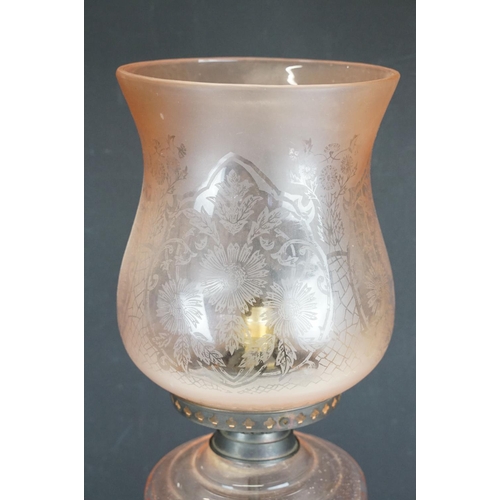174 - Late 19th / early 20th century oil lamp, the pink glass frosted shade with floral detail, over a gla... 