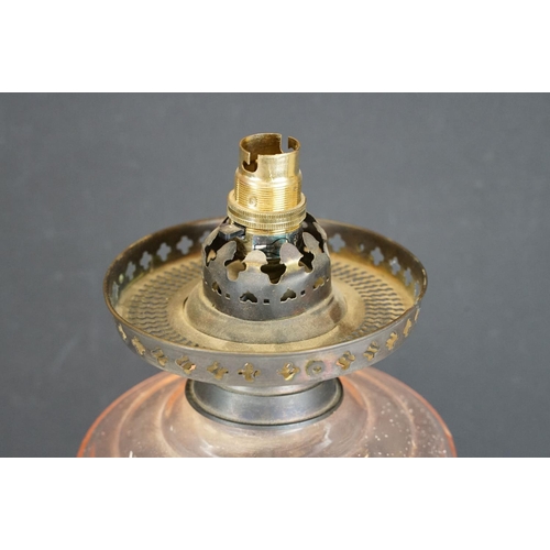 174 - Late 19th / early 20th century oil lamp, the pink glass frosted shade with floral detail, over a gla... 