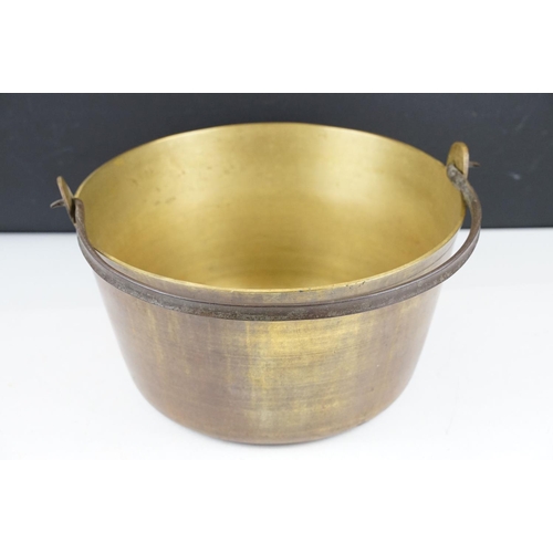 375 - A vintage brass preserve pan together with a clockwork and cast iron meat hanger.