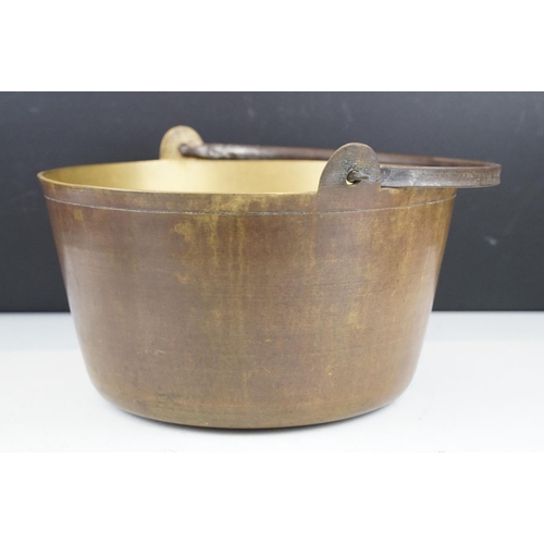 375 - A vintage brass preserve pan together with a clockwork and cast iron meat hanger.