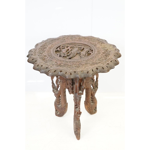 532 - Indian carved hardwood occasional table, the top carved with a central panel depicting three figures... 