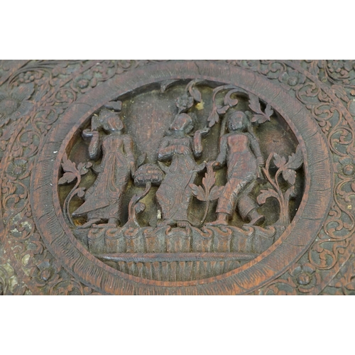 532 - Indian carved hardwood occasional table, the top carved with a central panel depicting three figures... 