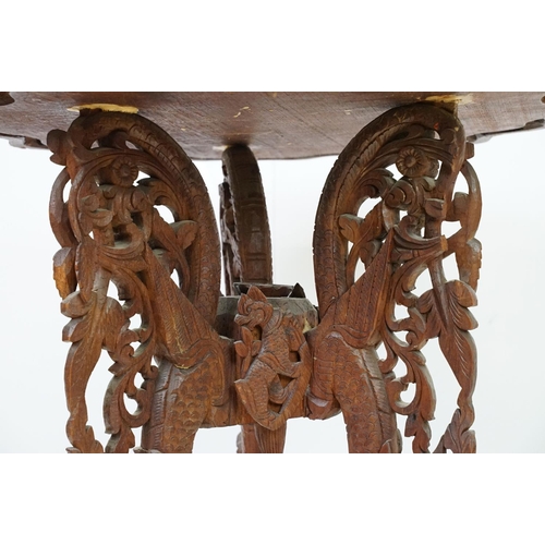 532 - Indian carved hardwood occasional table, the top carved with a central panel depicting three figures... 