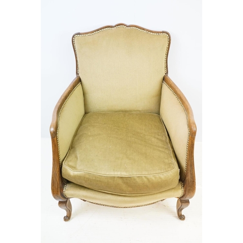 522 - Early 20th century low armchair with oak frame, upholstered in beige with studded edging, on cabriol... 