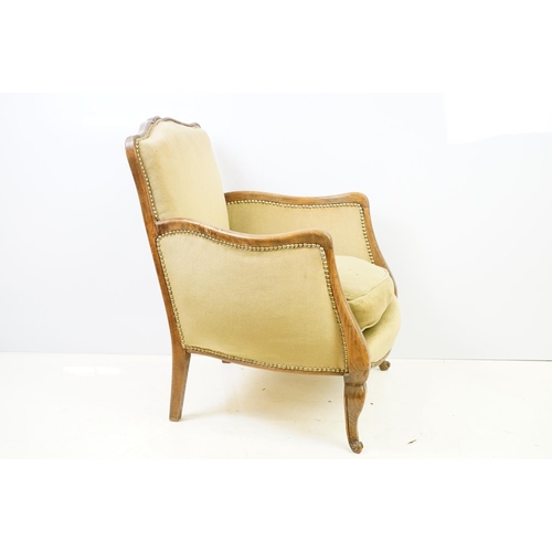 522 - Early 20th century low armchair with oak frame, upholstered in beige with studded edging, on cabriol... 