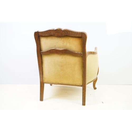 522 - Early 20th century low armchair with oak frame, upholstered in beige with studded edging, on cabriol... 