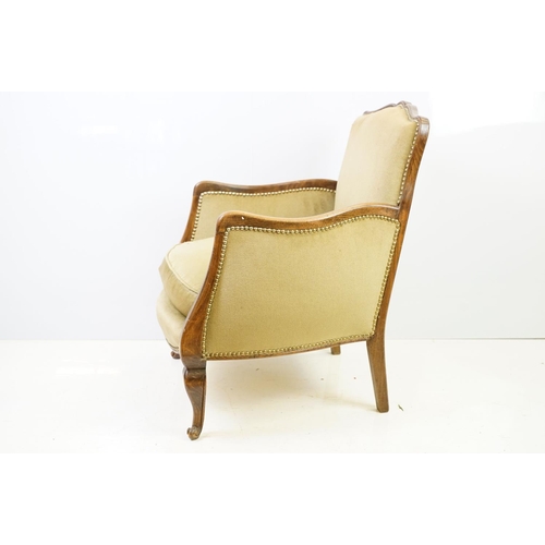 522 - Early 20th century low armchair with oak frame, upholstered in beige with studded edging, on cabriol... 