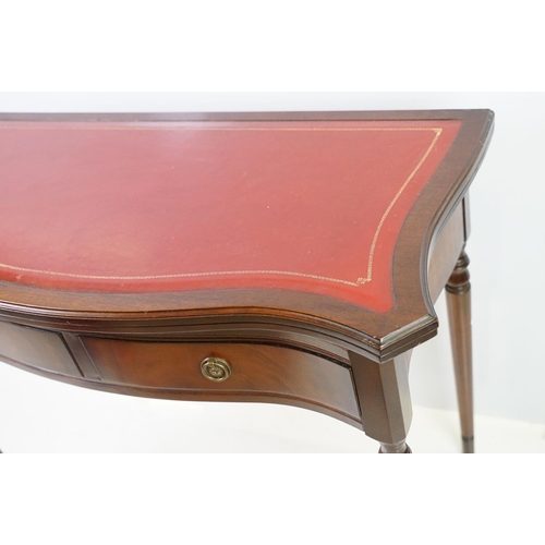 567 - 20th century mahogany games table with red leather inset top of serpentine form, top swivels to reve... 