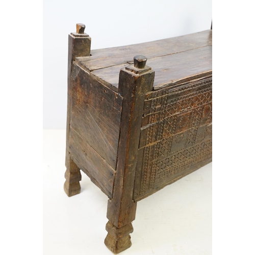 569 - 18th / 19th century Eastern coffer / blanket box, with naively carved panel front and four posts and... 