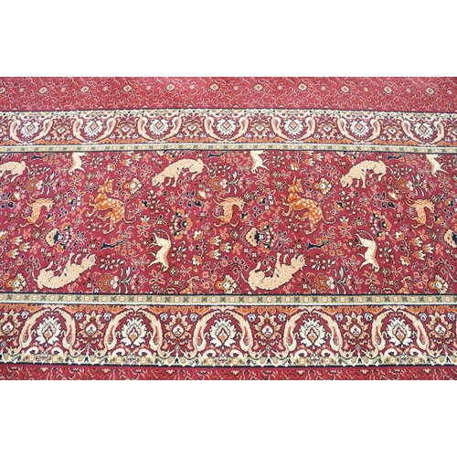 593 - Burgundy ground carpet, the central panel decorated with animals, within a border, 200cm wide x 415c... 