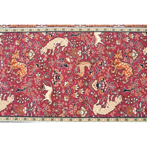 593 - Burgundy ground carpet, the central panel decorated with animals, within a border, 200cm wide x 415c... 