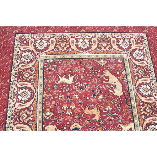 593 - Burgundy ground carpet, the central panel decorated with animals, within a border, 200cm wide x 415c... 