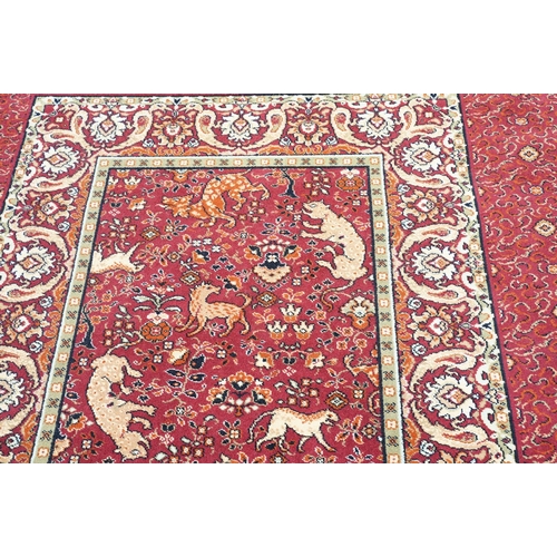 593 - Burgundy ground carpet, the central panel decorated with animals, within a border, 200cm wide x 415c... 