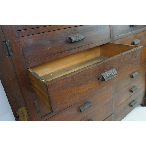 597 - Early 20th century mahogany chest of fourteen drawers, with decorative cast iron handles, with two l... 