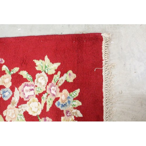 574A - Large red ground wool floor rug with floral decoration, fringe to either end, measures approx 260cm ... 