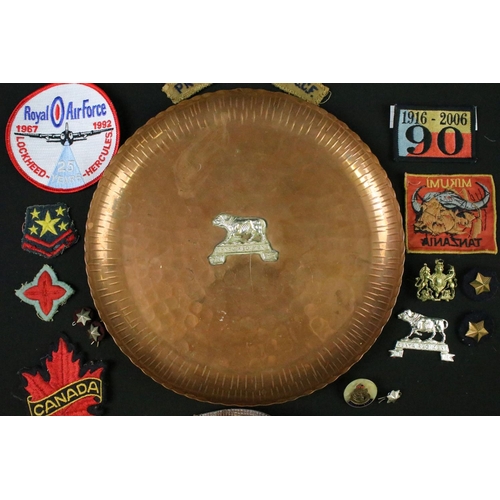 125 - A vintage hammered copper dish badged to the Kenya Regiment together with a quantity of military clo... 