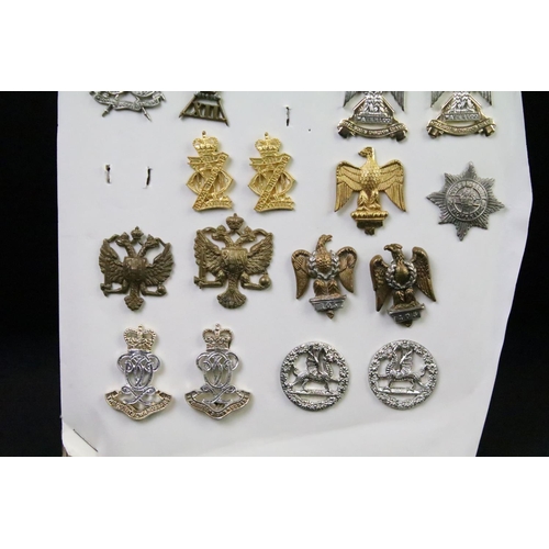 43 - A collection of British military regimental cap and collar badges to include the Devonshire regiment... 