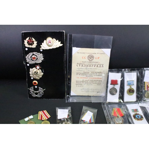 70 - A collection of Russian / CCCP medals and cap badges to include World War Two examples.