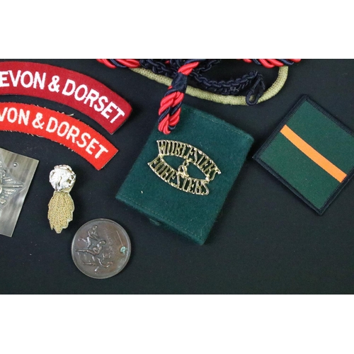 75 - A collection of mixed military collectables to include cloth badges, shoulder titles, lanyards, ciga... 