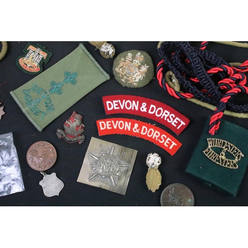 75 - A collection of mixed military collectables to include cloth badges, shoulder titles, lanyards, ciga... 