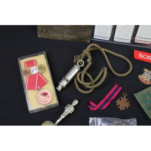 75 - A collection of mixed military collectables to include cloth badges, shoulder titles, lanyards, ciga... 