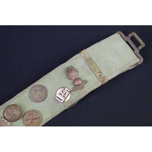 76 - A military webbing belt with attached buttons and cap badges.