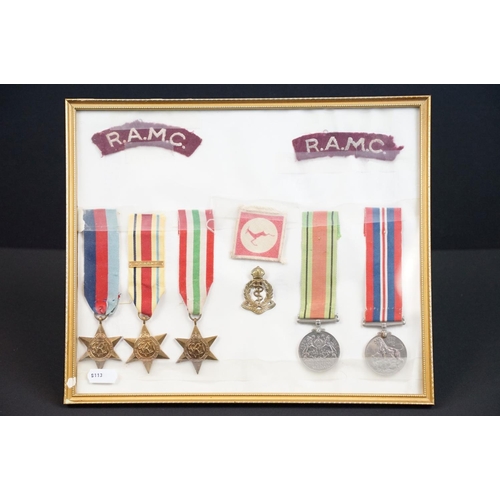 134 - A framed and glazed World War Two medal group of five full size medals together with badges to the R... 