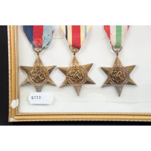 134 - A framed and glazed World War Two medal group of five full size medals together with badges to the R... 