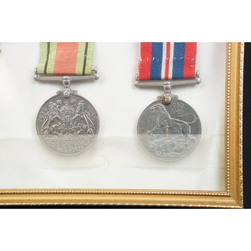 134 - A framed and glazed World War Two medal group of five full size medals together with badges to the R... 