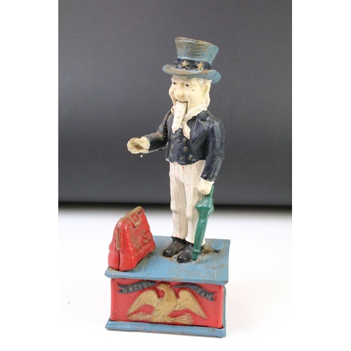 141 - Two reproduction cast iron money boxes to include a Punch and Judy box and an Uncle Sam example. Lar... 