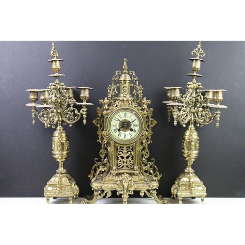 143 - Cast brass clock garniture set clock of scrolling form, the clock with pierced design, cream dial an... 