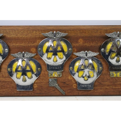 151 - Automobilia - A wall display of nine AA grill badges and AA key, all mounted on a wooden panel. (Mea... 