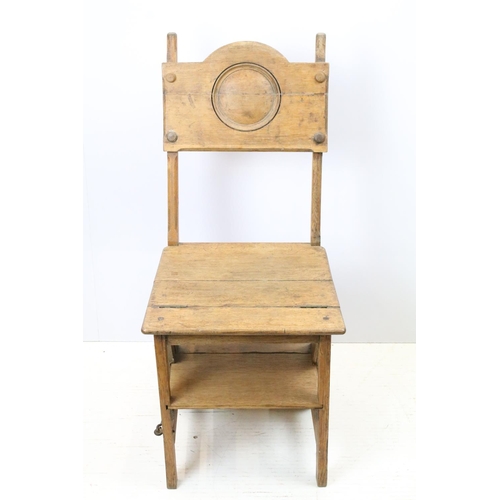 653 - Arts and Crafts metamorphic library chair, the arched backrest with a central circular panel, on cha... 
