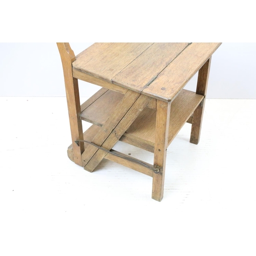 653 - Arts and Crafts metamorphic library chair, the arched backrest with a central circular panel, on cha... 