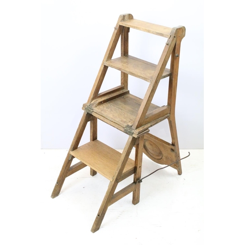 653 - Arts and Crafts metamorphic library chair, the arched backrest with a central circular panel, on cha... 