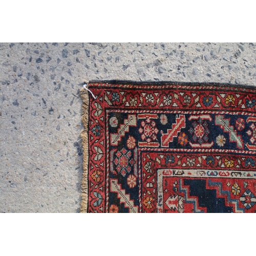 669 - Middle Eastern red ground rug, with central medallion and two half medallions, 197cm x 132cm