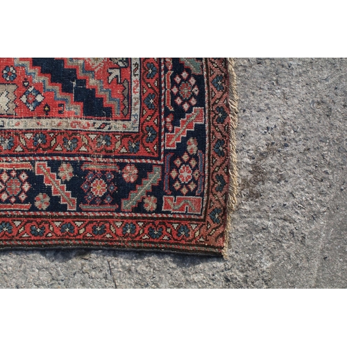 669 - Middle Eastern red ground rug, with central medallion and two half medallions, 197cm x 132cm