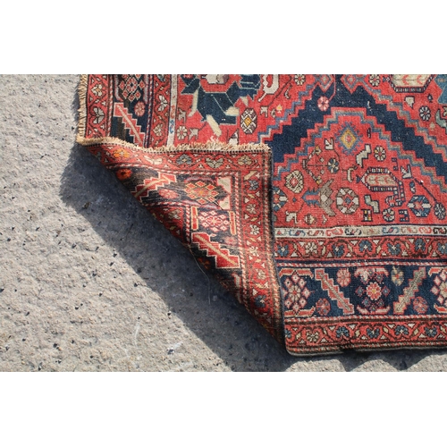 669 - Middle Eastern red ground rug, with central medallion and two half medallions, 197cm x 132cm