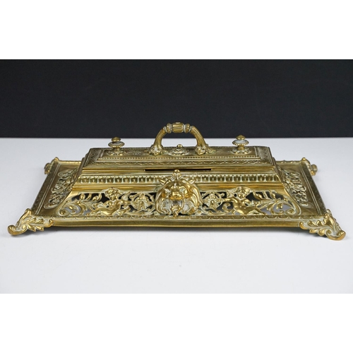 106 - Cast brass inkstand with ornate scrolling and lion mask detail, with hinged cover, approx 35cm wide