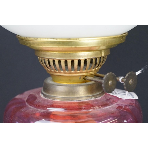 111 - Early 20th century brass oil lamp, the white glass shade with floral detail, with cranberry glass fo... 