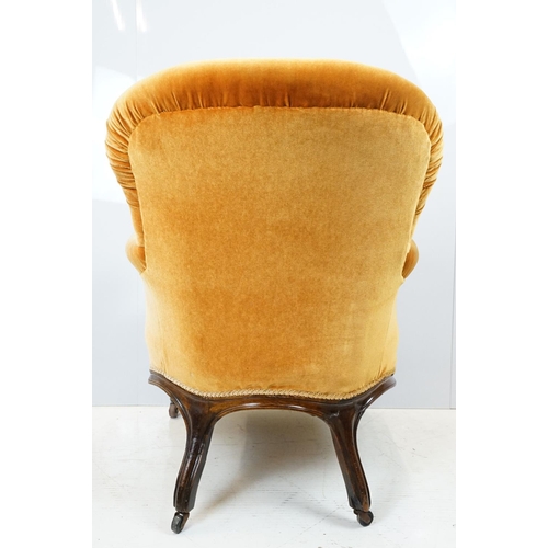 654 - Early 20th century wing back armchair of curved form, with button back, upholstered in orange, on tu... 