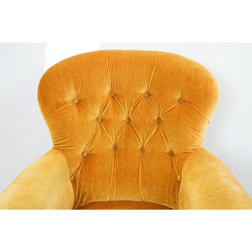 654 - Early 20th century wing back armchair of curved form, with button back, upholstered in orange, on tu... 