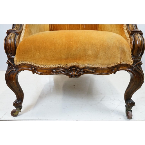 654 - Early 20th century wing back armchair of curved form, with button back, upholstered in orange, on tu... 