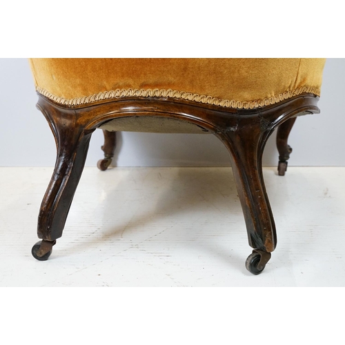 654 - Early 20th century wing back armchair of curved form, with button back, upholstered in orange, on tu... 