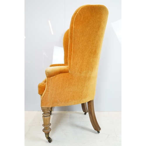654 - Early 20th century wing back armchair of curved form, with button back, upholstered in orange, on tu... 