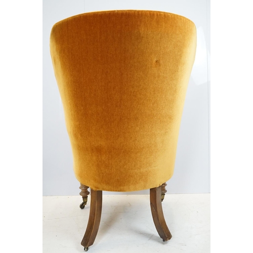 654 - Early 20th century wing back armchair of curved form, with button back, upholstered in orange, on tu... 